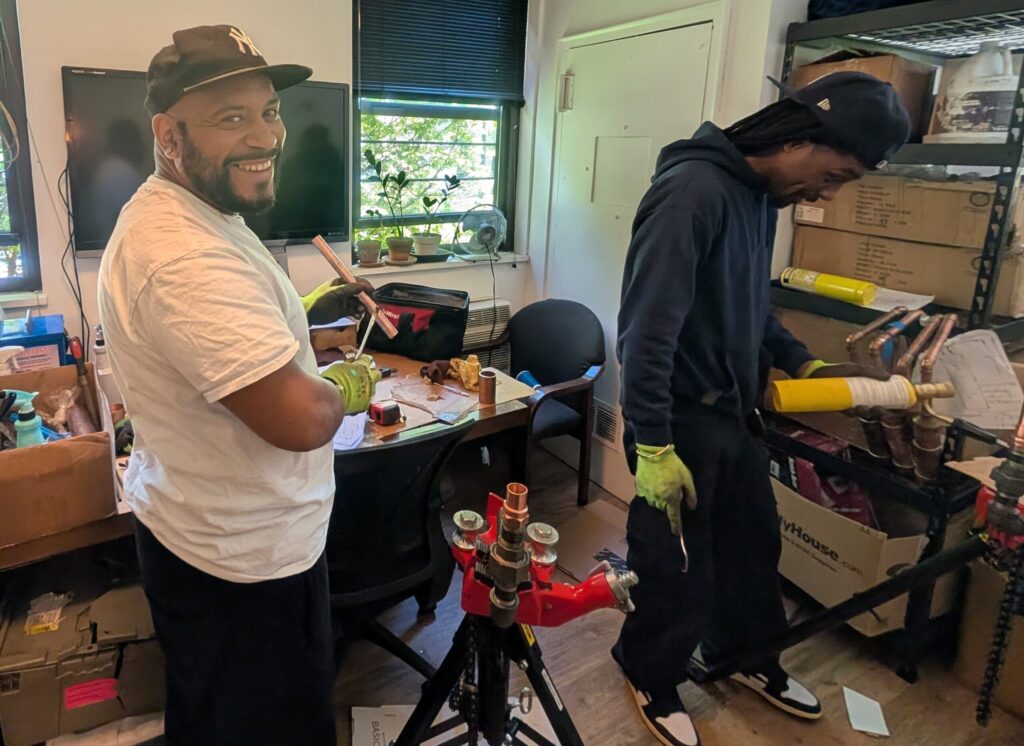 Team members soldering copper pipe