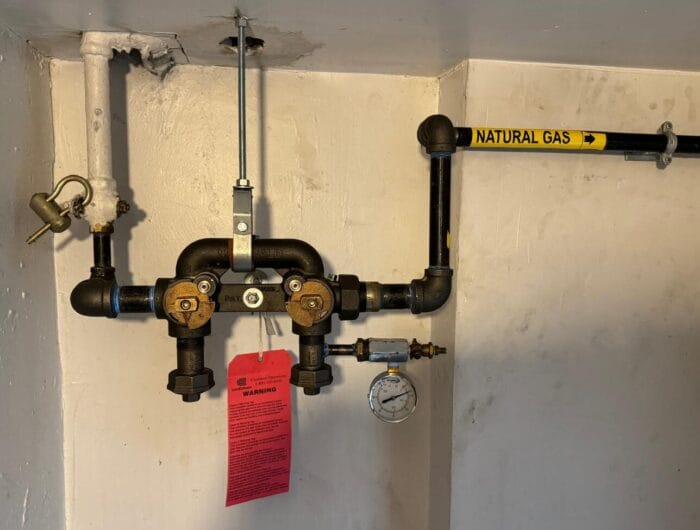 Natural gas piping and meter bar with Con Edison red tag indicating gas shutoff