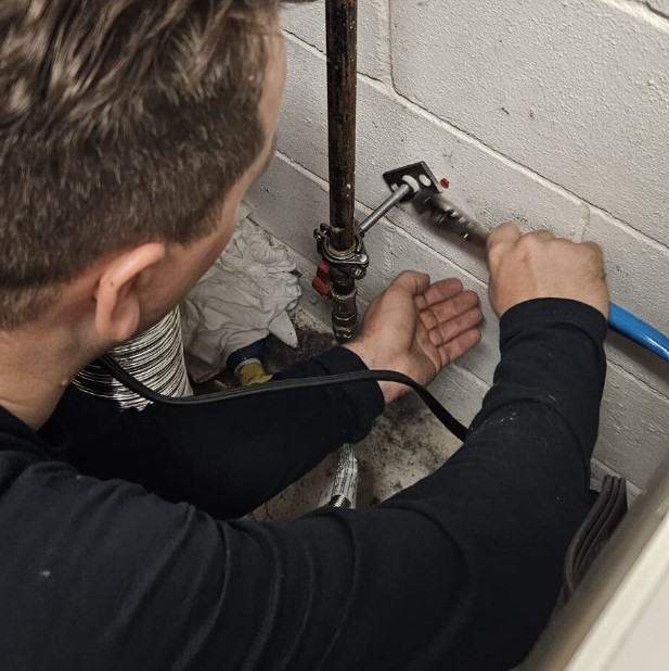 Ariel Services, Inc. plumber using wrench to install pipe support hanger