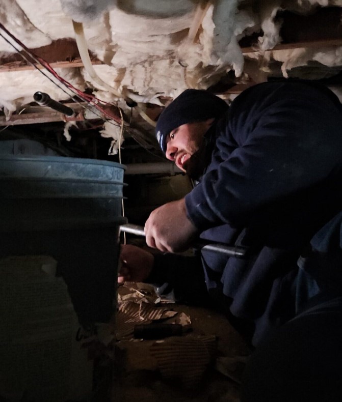 Ariel Services, Inc. plumber installing steel pipe in New York City crawlspace