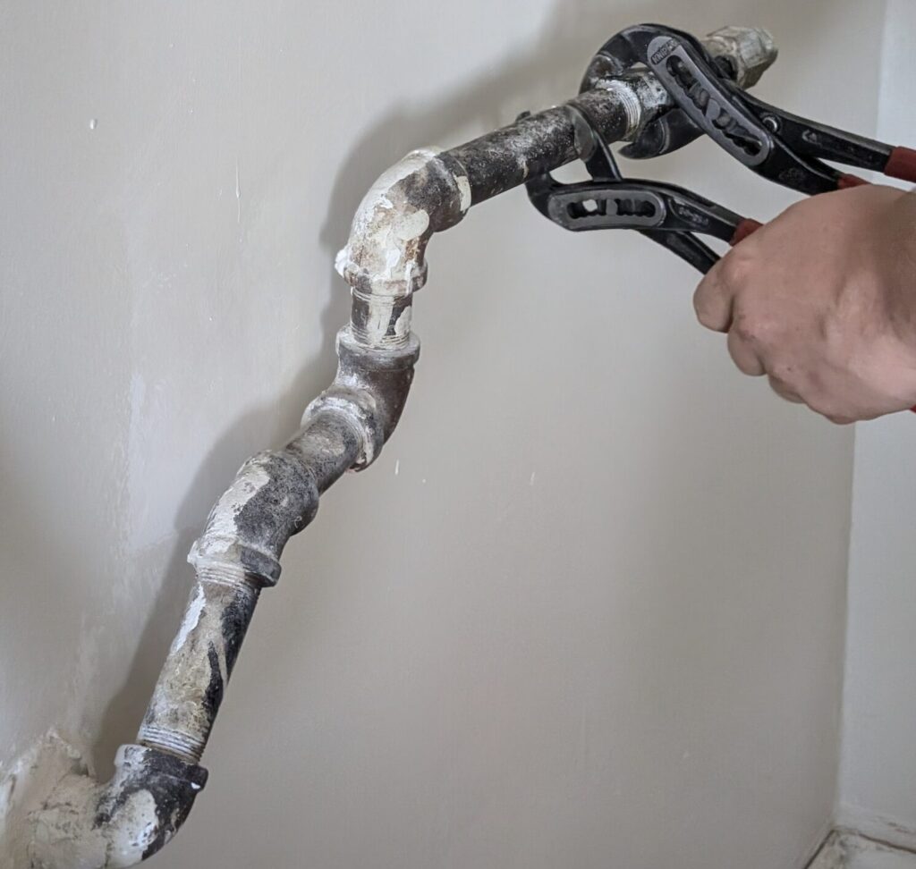 Ariel Services plumber using 2 channel locks to remove old gas piping to be replaced