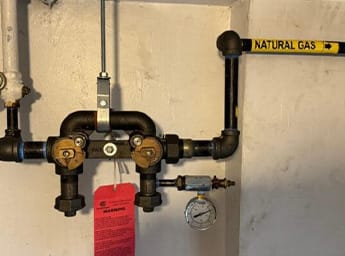 Natural gas piping and meter bar with Con Edison red tag indicating gas shutoff